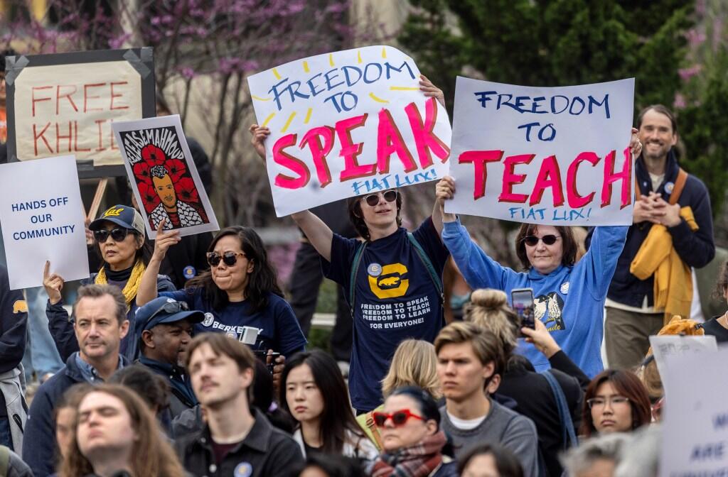 Demonstrators at the Rise Up for Education Rally. Two hold signs saying, "Freedom to Speak, Fiat Lux!" and "Freedom to Teach, Fiat Lux!"